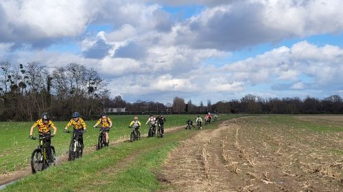 Les jeunes vététistes à vélo en file indienne sur un chemin bien terreux.